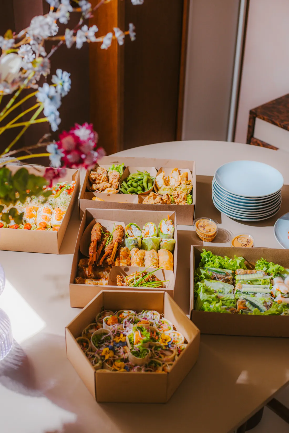 Stół z boxami cateringowymi Camon: karaage z edamame, szaszłyki, sajgonki i mini tortille z kwiatami, catering w Białymstoku